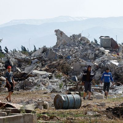 Syrian youths walk amongst the rubble in the village of al-Hamidiyeh, north of Qusayr, in Syria's central Homs province on June 7, 2013 as regime forces sought to mop up the final pockets of rebel resistance north of Qusayr, after retaking the key town that was an insurgent bastion for a year, a watchdog said. Qusayr's capture gives President Bashar al-Assad the upper hand if a US-Russian plan for the first direct peace talks with his opponents materialises, analysts say.