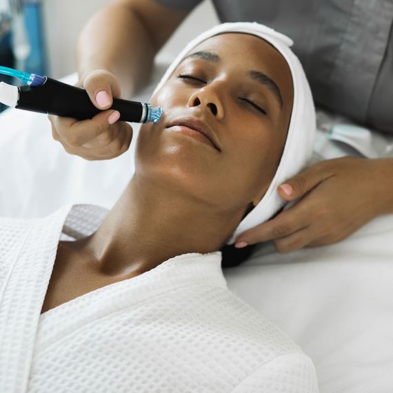 Closeup of face of beautiful relaxing african girl undergoing hardware cosmetology procedure in spa.
