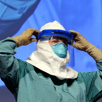 Barbara Smith, RN,(screen-R) Mount Sinai Health Sysytems demonstrates the proper technique for donning and removing protective gear during an ebola educational session for healthcare workers at the Jacob Javits Center in New York on October 21, 2014. AFP PHOTO / Timothy A. Clary (Photo credit should read TIMOTHY A. CLARY/AFP/Getty Images)