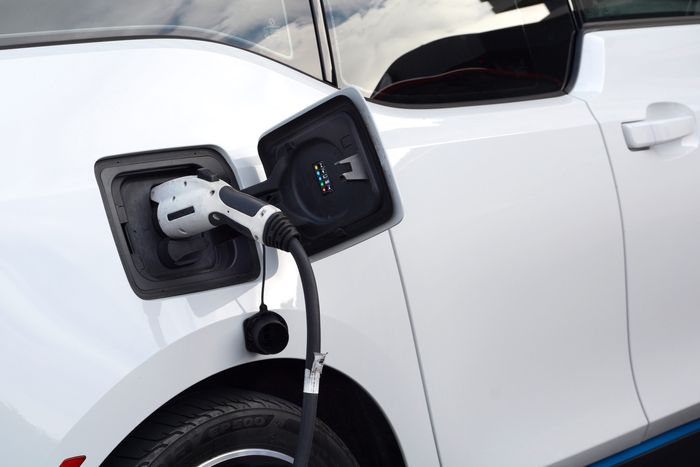 A photo of a white electric vehicle with a charger plugged in.