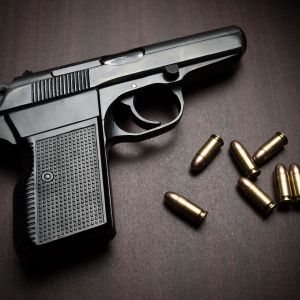handgun with bullets on the wooden surface, closeup with vignette, useful for various security,protection or criminal topics