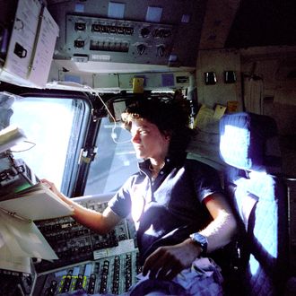American astronaut Sally K. Ride, mission specialist on STS-7, monitors control panels from the pilot's chair on the Flight Deck. Floating in front of her is a flight procedures notebook june 25, 1983.