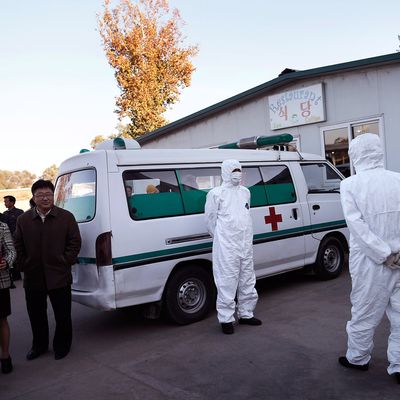27 Oct 2014, Pyongyang, North Korea --- Medical staff are dressed in protective suits as they wait by an ambulance, at the Sunan International Airport, Monday, Oct. 27, 2014 in Pyongyang, North Korea. North Korea last week stepped up its measures to prevent the spread of the Ebola virus while a major travel agency that specializes in tours to the reclusive country said it had been informed Pyongyang may ban foreign tourists from visiting.(AP Photo/Wong Maye-E) --- Image by ? Wong Maye-E/AP/Corbis