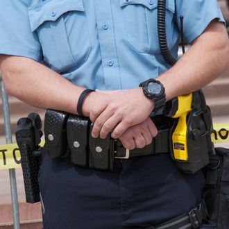 Policeman carries a gun on his right and a taser on his left, part of a force protecting members of the neo-Nazi National Socialist Movement as they held a rally on the steps of the government office building, Toledo, Ohio, United States, North Ameri