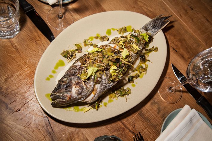 Whole roasted black sea bass is cooked on a wood grill.