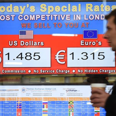 A pedestrian passes a euro dollar currency exchange rate screen in London, Britain, 26 January 2015. 