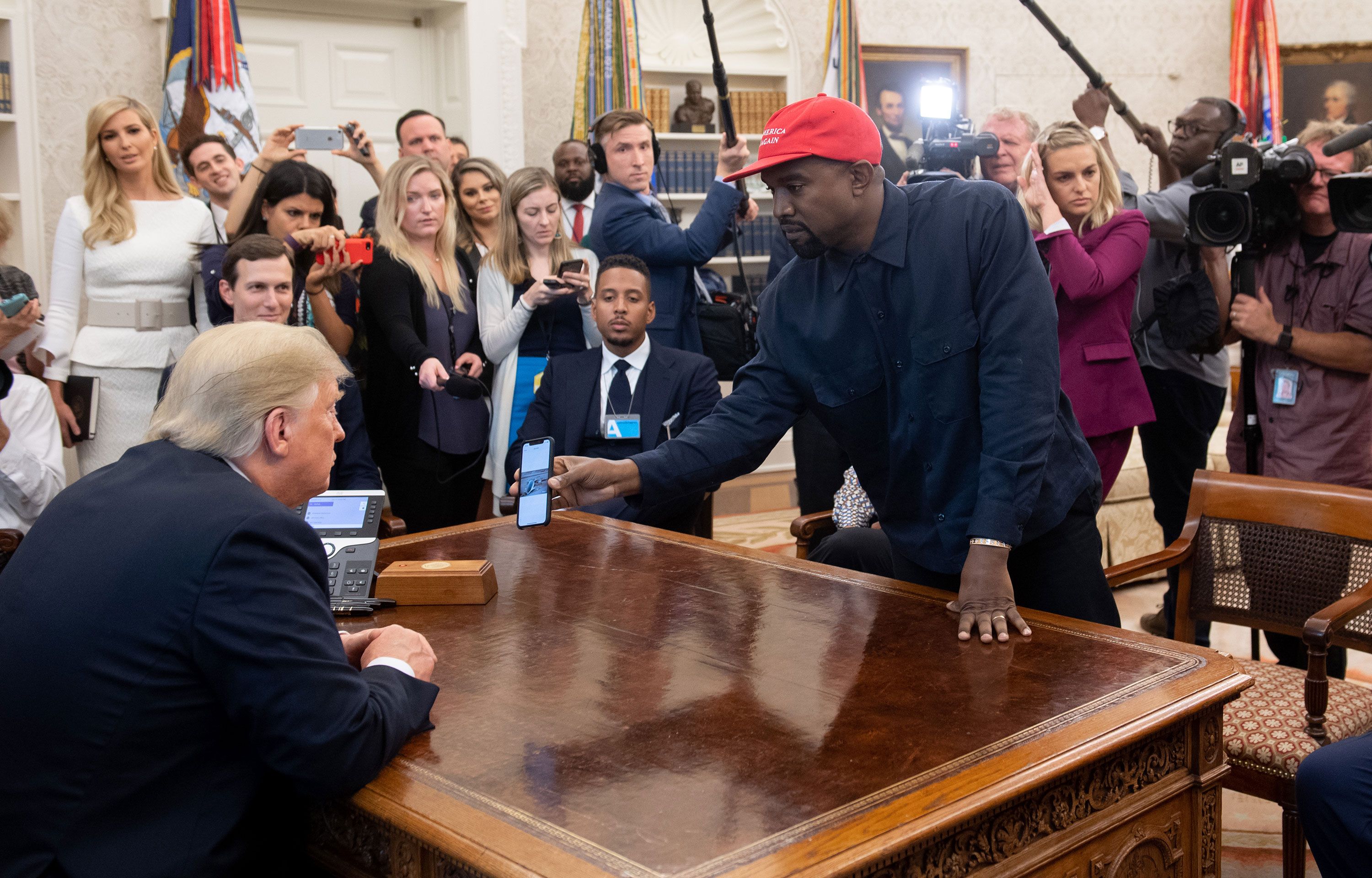 Kanye west smiling, dressed in the us president's suit in front of the  white house