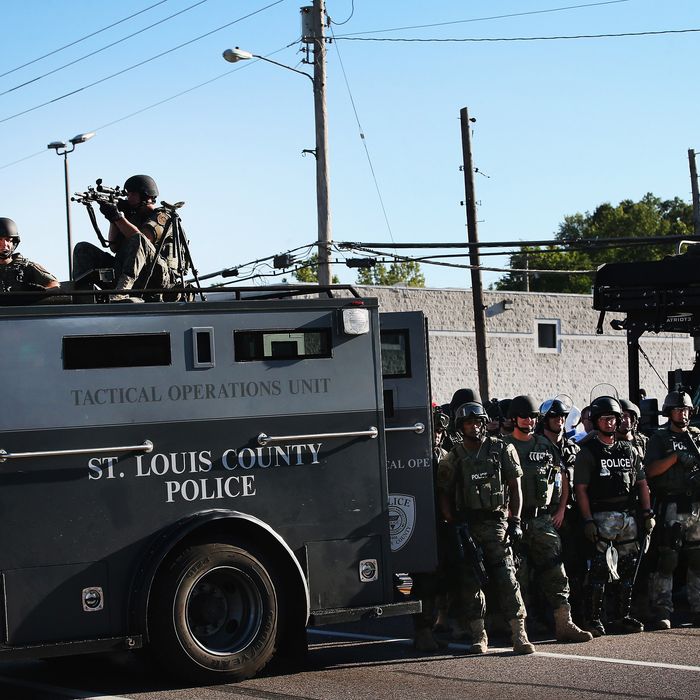 FERGUSON, MO - AUGUST 13: Police stand watch as demonstrators protest the shooting death of teenager Michael Brown on August 13, 2014 in Ferguson, Missouri. Brown was shot and killed by a Ferguson police officer on Saturday. Ferguson, a St. Louis suburb, is experiencing its fourth day of violent protests since the killing. (Photo by Scott Olson/Getty Images)