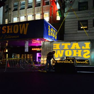 Workers remove the 'Late Show with David Letterman' sign on the Ed Sullivan Theater marquee in New York City, NY