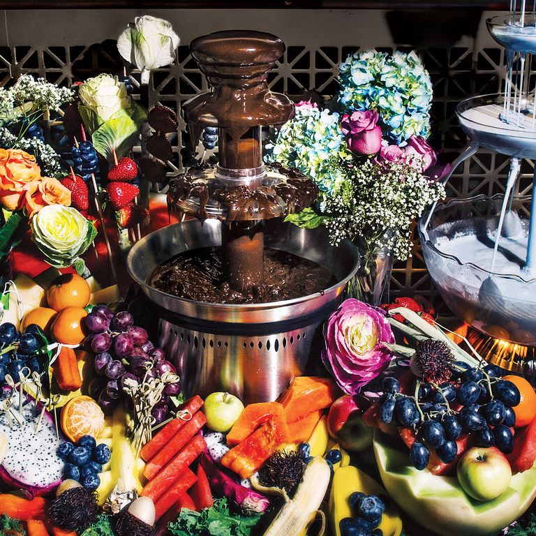 巧克力喷泉和椰子蓝色打孔。客人将水果浸入巧克力中。