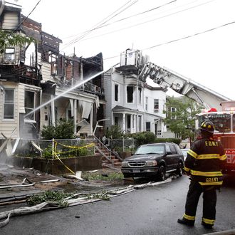 A firefighter, right, watches as another sprays water on 205 Chestnut Avenue in the Staten Island borough of New York, Thursday, June 5, 2014, where 34 people were injured after fire tore through three townhouses on the street early Thursday. Two children were tossed out of a smoke-filled second-story window into the arms of neighbors below, according to authorities and witnesses. (AP Photo/Kathy Willens)