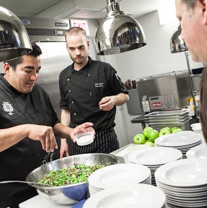Iron Chef Jose Garces seasons fava beans as his sous chef (Louis) and Chef Paul Kahan look on.
