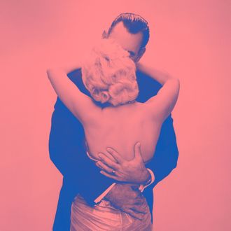 05 Jul 1956 --- 1950s 1960s kissing couple blond woman backless satin evening dress man embracing from behind --- Image by ? Ewing Galloway/ClassicStock/Corbis