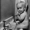 Adorable baby brushing teeth while sitti