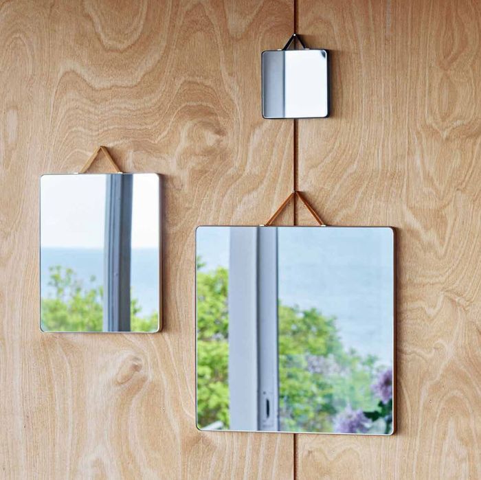 set of mirrors reflecting flowers set against a wooden backdrop - strategist best decorative mirrors