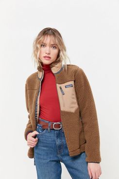 A short Patagonia Retro-X brown fleece jacket with smooth light tan accents, a zipper breast pocket, and a high neck, shown on a model wearing a fitted red turtleneck, high waisted mom jeans, and a brown belt with a silver buckle. The Strategist - 48 Things on Sale You’ll Actually Want to Buy: From Sunday Riley to Patagonia