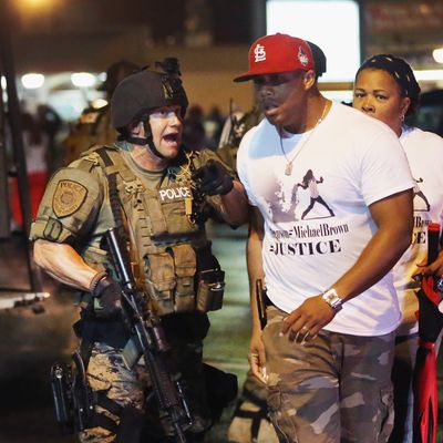 FERGUSON, MO - AUGUST 15: Police confront demonstrators during a protest over the shooting of Michael Williams on August 15, 2014 in Ferguson, Missouri. County police shot pepper spray, smoke, gas and flash grenades at protestors before retreating. Several businesses were looted as county police watched from their armored personnel carriers (APC) parked nearby. Violent outbreaks have taken place in Ferguson since the shooting death of Brown by a Ferguson police officer on August 9. (Photo by Scott Olson/Getty Images)
