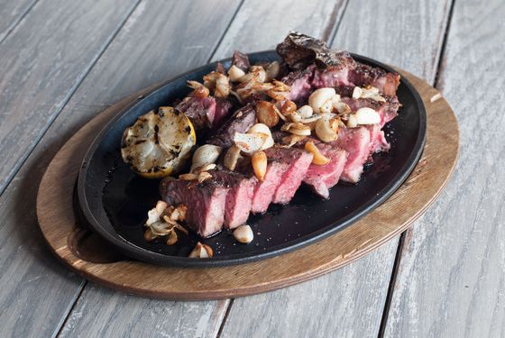 25-day dry-aged beef porterhouse (for three) served sliced, off the bone, with crispy garlic and lemon.