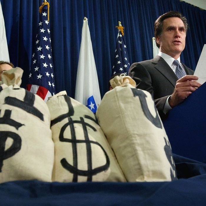 With money bag props at his side, Massachuetts Gov. Mitt Romney reads a bar chart regarding potential changes to the unemployment insurance laws during a news conference at the Statehouse in Boston, Tuesday, Nov. 25, 2003.