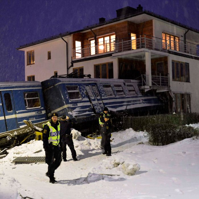 Policemen stand in front of a local train that derailed into a residential building in Saltsjoebaden, Sweden, on January 15, 2013. A domestic cleaner stole the train and drove it into the building and was taken to hospital after the crash.