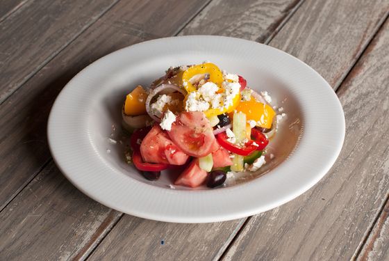 Greek village salad with tomato, cucumber, olives, peppers, feta, and oregano.