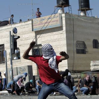 A masked Palestinian protestor uses a sling to throw stones toward Israeli police during clashes in Shuafat neighborhood in Israeli-annexed Arab East Jerusalem, on July 2, 2014, after a Palestinian teenager was kidnapped and killed in an apparent act of revenge for the murder by militants of three Israeli youths. 