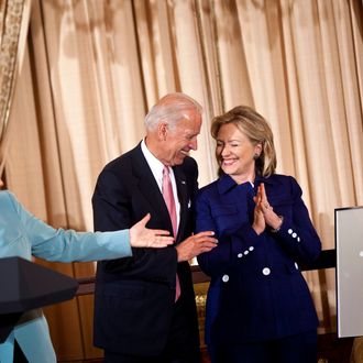 Vice President Joseph R. Biden (C) watches as German Chancellor Angela Merkel (L) presents a front page clipping from the Frankfurter Allgemeine to Secretary of State Hillary Rodham Clinton of their hips during a luncheon at the US State Department June 7, 2011 in Washington, DC. Secretary of State Hillary Rodham Clinton and Vice President Joseph R. Biden hosted German Chancellor Angela Merkel for a luncheon during her visit to Washington before tonight's State Dinner. 