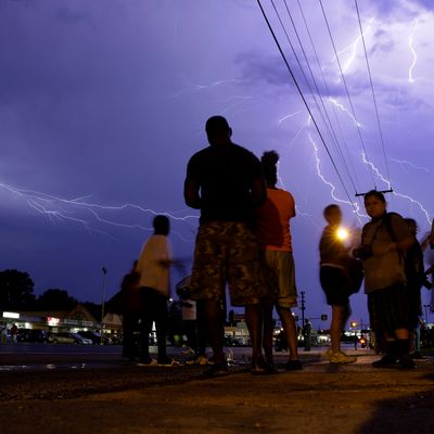 Protesters stand in the street as lightning fills the night sky Wednesday, Aug. 20, 2014, in Ferguson, Mo. A grand jury has begun hearing evidence as it weighs possible charges against the Ferguson police officer who fatally shot 18-year-old Michael Brown. (AP Photo/Jeff Roberson)