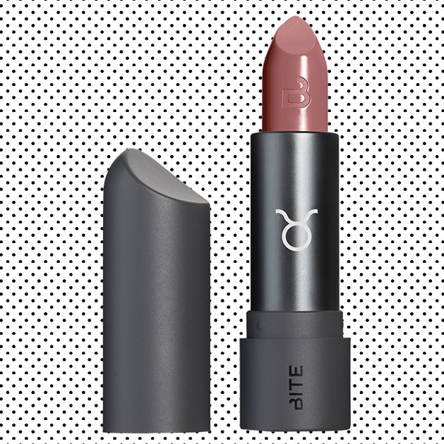 A subtle, muted rosy lipstick shade in a black lipstick tube that has the Taurus symbol on the front