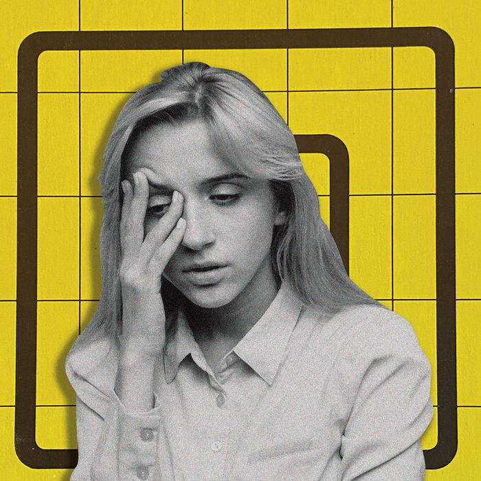 A woman with long, light-colored hair wearing a button-down shirt buttoned up to her neck hold her face in her right hand, two of her fingers tugging at her eyebrow in an expression of concern.