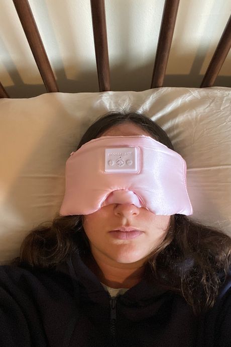 A person wearing a pink sleep mask.