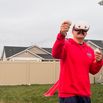 A man wearing a VR headset, holding two controllers, standing outside using the headset.