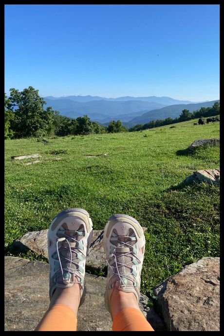 A photo of a person's feet, wearing gray shoes, on a mountain.