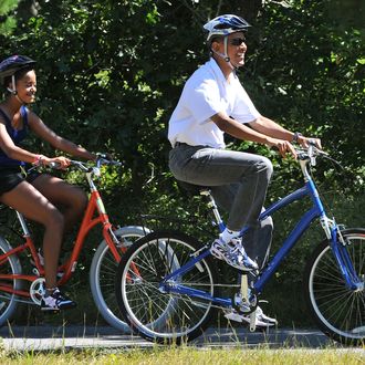 US President Barack Obama rides his bicycle as he is followed by his daughter Malia in West Tisbury on Martha's Vineyard, Massachusetts, on August 27, 2010. The US First Family is vacationing on the island until August 29. AFP PHOTO/Jewel Samad (Photo credit should read JEWEL SAMAD/AFP/Getty Images)