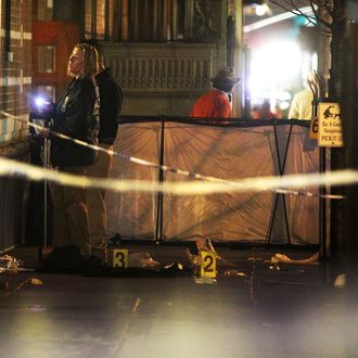 Police (L) investigate the scene of a fatal shooting on W. 58th Street in Manhattan on December 10, 2012 in New York City. A 31-year-old man was shot in the head in the broad daylight and has since been pronounced dead.