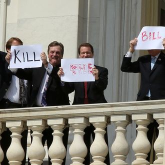 Members of Congress hold up signs from the second floor of the Capitol that read 