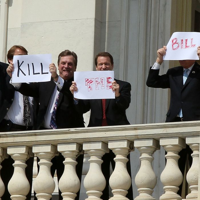 Members of Congress hold up signs from the second floor of the Capitol that read