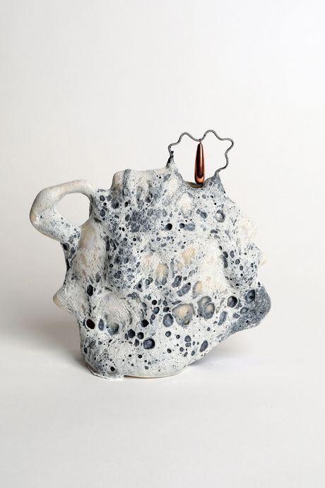 A ceramic vessel with cratery greyish blue glaze that looks like the surface of the moon