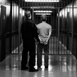 A prison guard leading a prisoner along a corridor