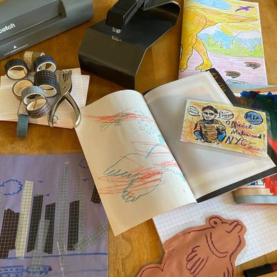 Photo of a wooden table with a variety of office supplies including scissors, a laminator, a stapler, and washi tape on top.