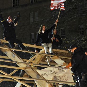 Occupy DC protesters wave to their supporters before their arrest atop a wooden structure at their encampment at McPherson Square in Washington on December 4, 2011. The police moved in to remove the structure the demontrators erected illegally and arrested several protesters. AFP PHOTO/Nicholas KAMM (Photo credit should read NICHOLAS KAMM/AFP/Getty Images)