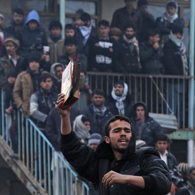 An Afghan demonstrator holds a copy of a half-burnt Koran, allegedly set on fire by US soldiers, at the gate of Bagram airbase during a protest against Koran desecration at Bagram, about 60 kilometres (40 miles) north of Kabul, on February 21, 2012.