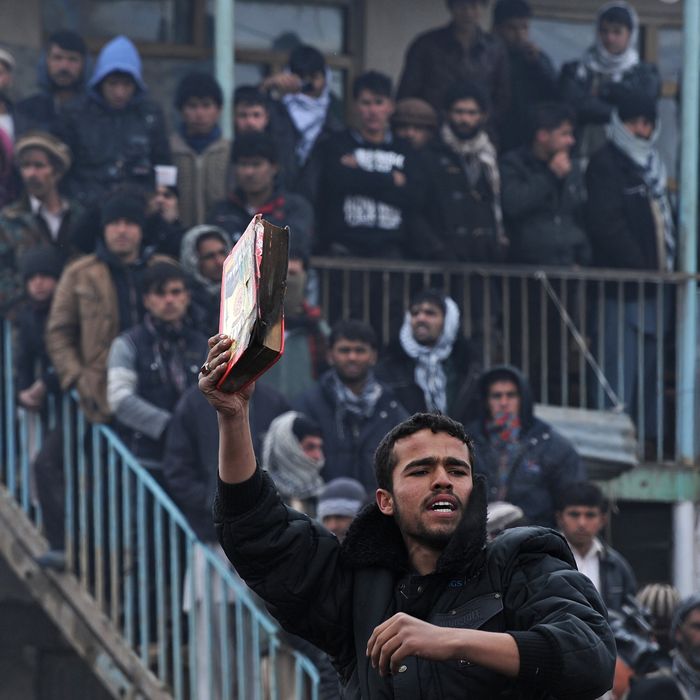 An Afghan demonstrator holds a copy of a half-burnt Koran, allegedly set on fire by US soldiers, at the gate of Bagram airbase during a protest against Koran desecration at Bagram, about 60 kilometres (40 miles) north of Kabul, on February 21, 2012.