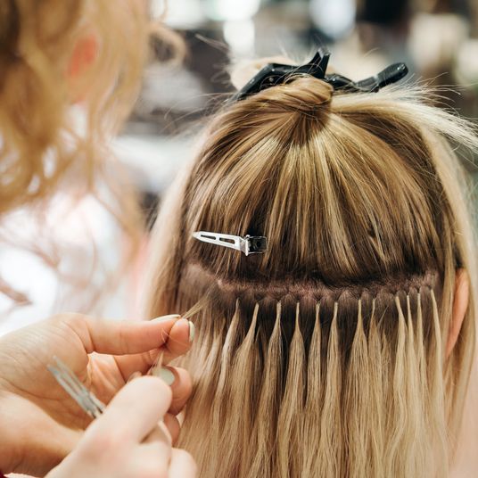 Girl hairdresser doing hairstyle styling for a middle-aged woman in a beauty salon