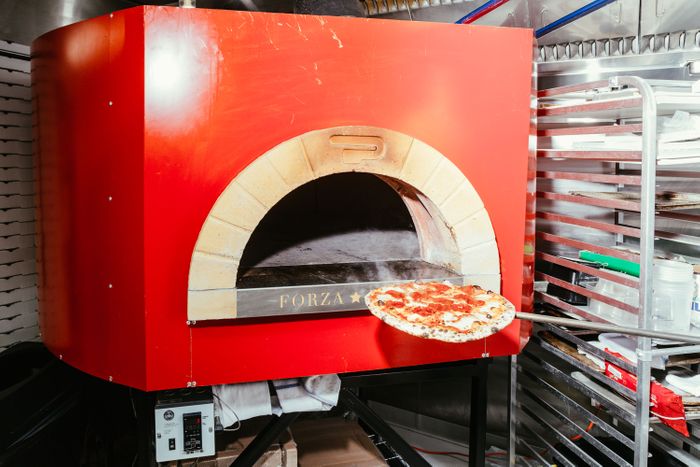 罗伯塔厨师从餐厅幽灵厨房大红炉中取披萨