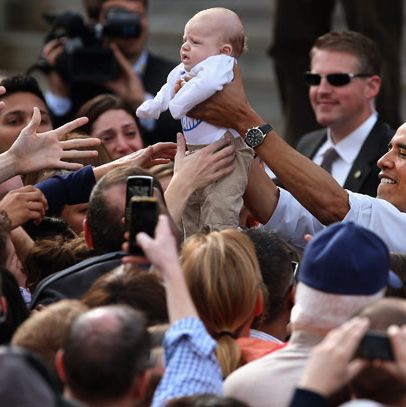 U.S. President Barack Obama lifts a baby handed to him from a supporter during a campaign rally at Elm Street Middle School October 27, 2012 in Nashua, New Hampshire. With ten days before the presidential election, Obama and his opponent, former Massachusetts Gov. Mitt Romney are criss-crossing the country from one swing state to the next in an attempt to sway voters.