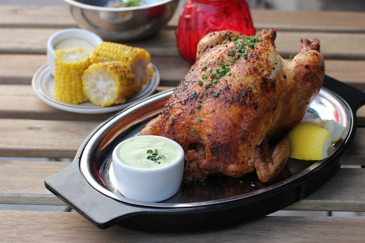 Whole rotisserie chicken with corn and green sauce.
