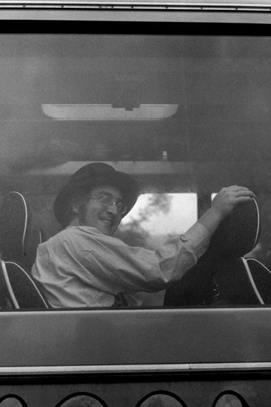 John Lennon looks back at the camera while filming Magical Mystery Tour on a bus.