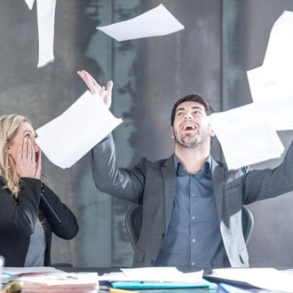 Businessman throwing papers in the air, woman looking shocked