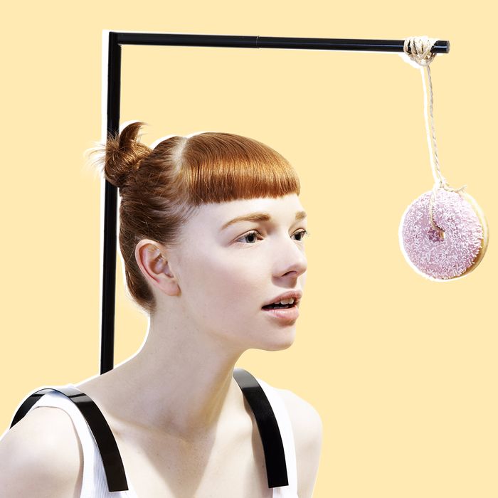 woman with donut dangling in front of face